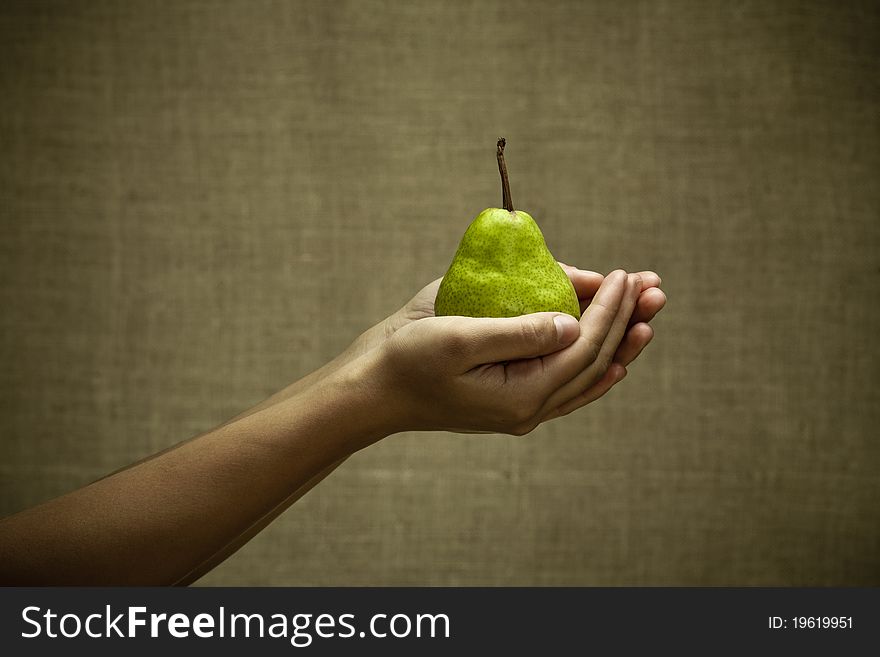 Green pear in female hands. Natural rural style image