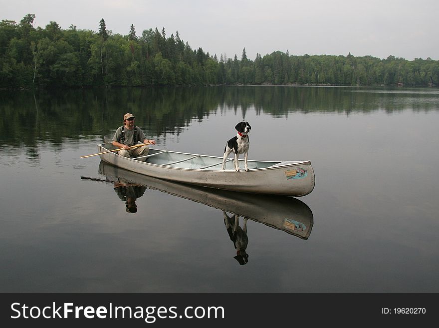 Canoeist with a Springer Spaniel dog in the bow of a canoe. Canoeist with a Springer Spaniel dog in the bow of a canoe