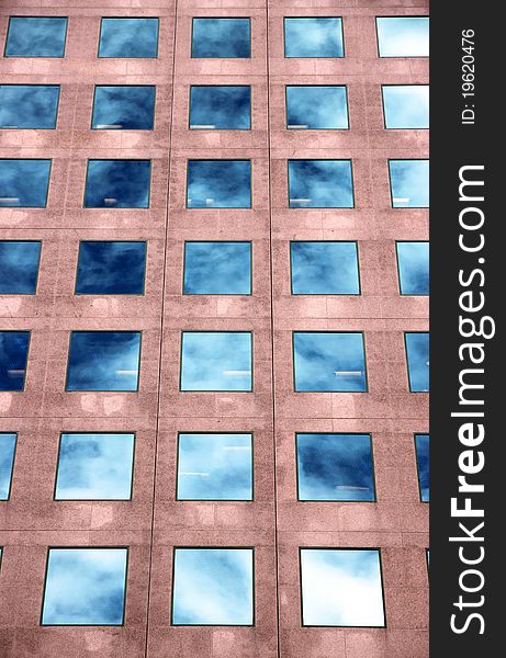 An office building with its windows reflecting the blue sky and white clouds. An office building with its windows reflecting the blue sky and white clouds