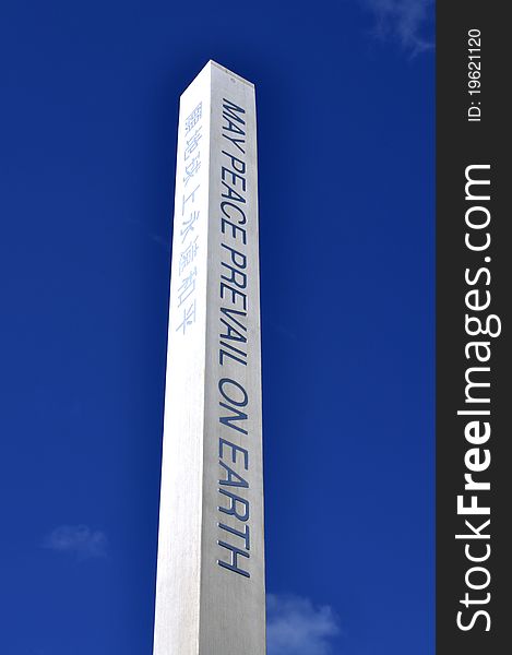 Tall peace pole stands beneath blue sky