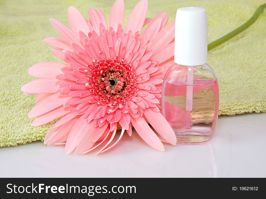 Nailcare product bottles with pink gerbera daisy flower and light green towel. Nailcare product bottles with pink gerbera daisy flower and light green towel