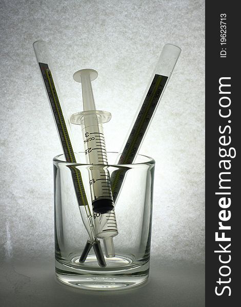 Syringe in glass on dark paper