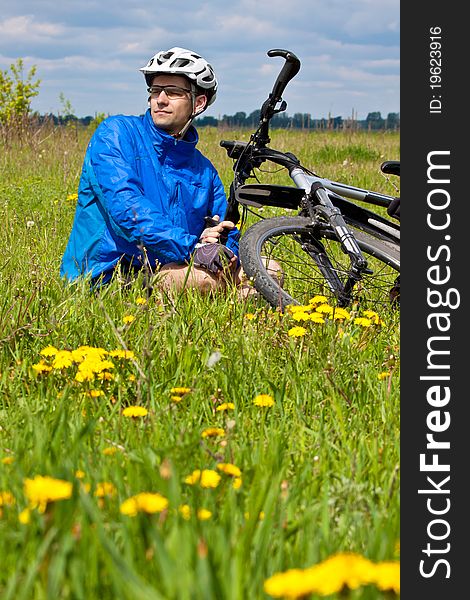 Mountain biker resting in a grass on sunne day