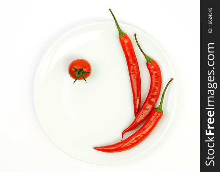 An image of red hot peppers with tomato on plate. An image of red hot peppers with tomato on plate