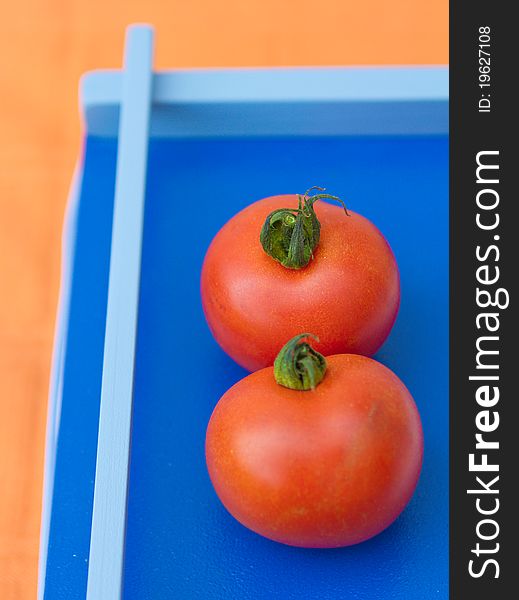 Two tomatoes on a blue background
