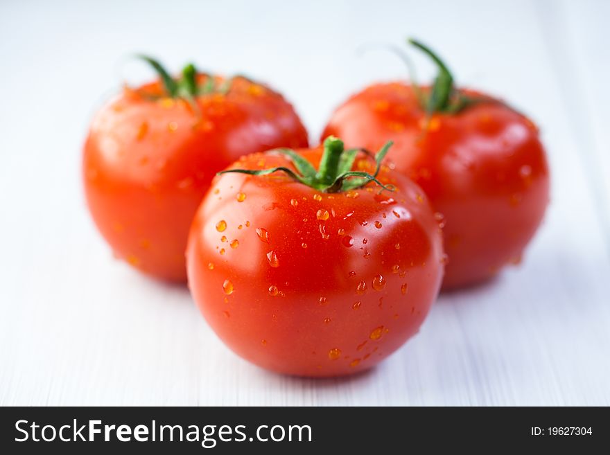 Three tomatoes on wooden white background