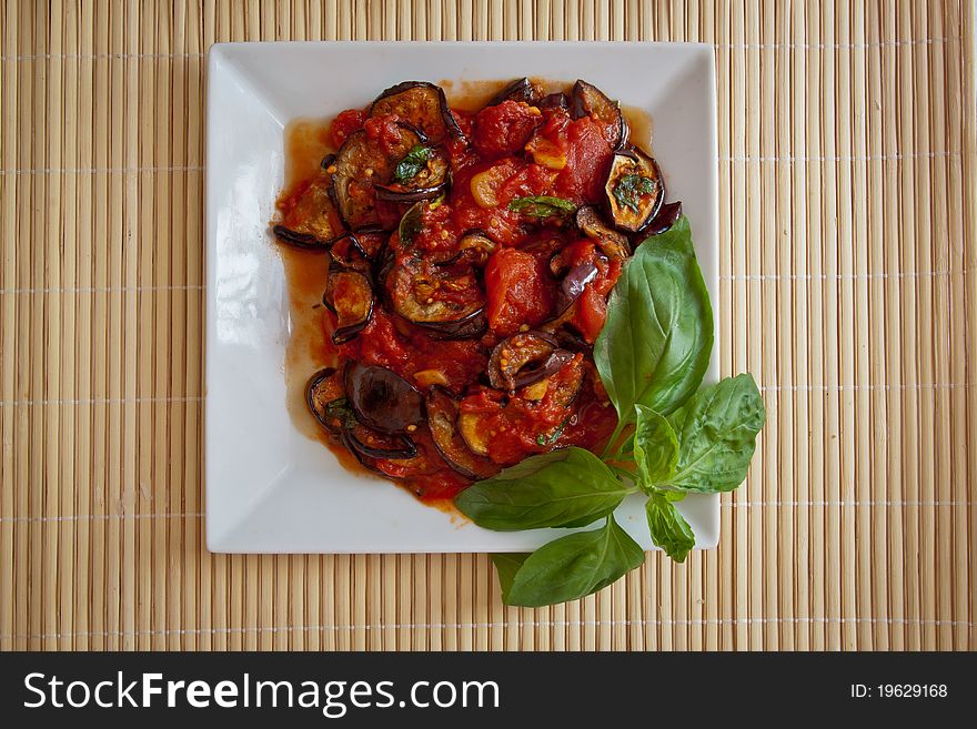 Platter of grilled aubergines in a tomato sauce with basil. Plenty of copy space. Platter of grilled aubergines in a tomato sauce with basil. Plenty of copy space.