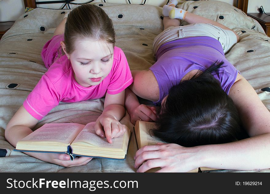 Mother And Daughter Reading In Bed Book