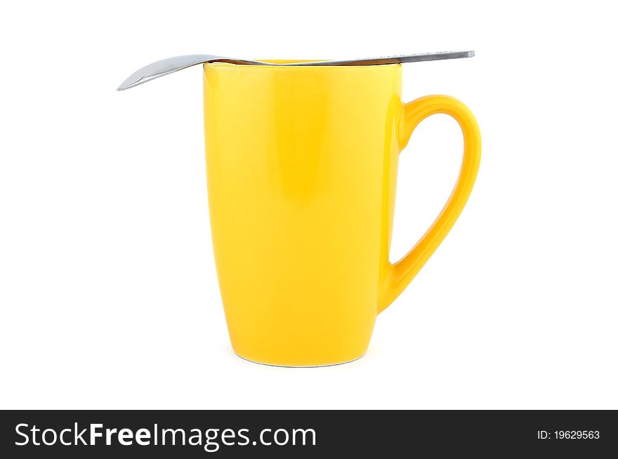 Empty yellow cup and spoon on a white background