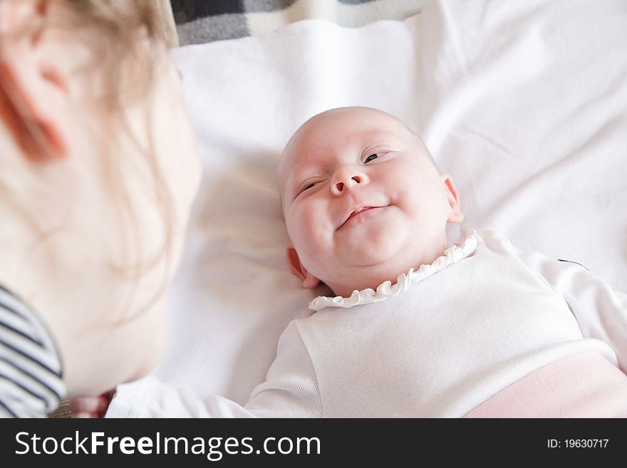 Little smiling newborn girl looking on her mother. Little smiling newborn girl looking on her mother