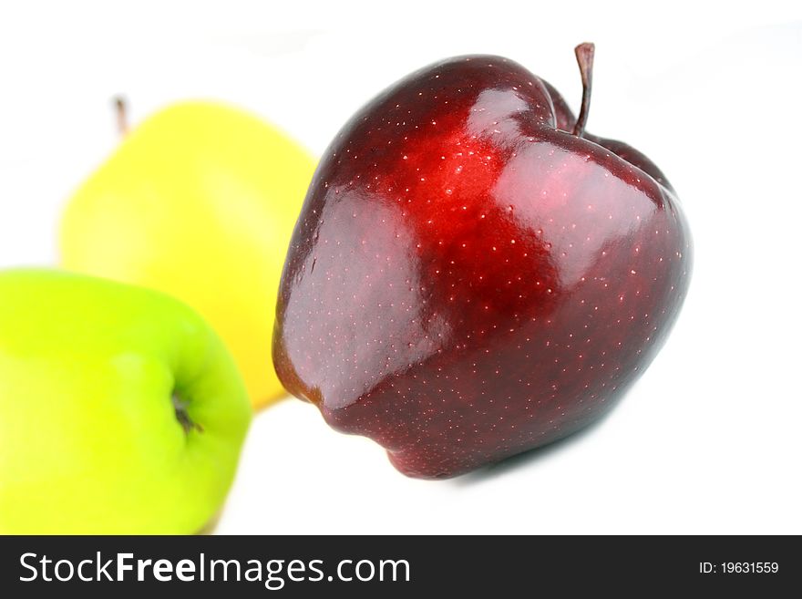 Three different color apples, focus on red one