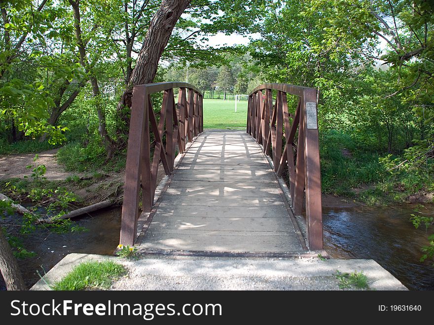 A Bridge crossing silvercreek, leading to an open sports field. A Bridge crossing silvercreek, leading to an open sports field