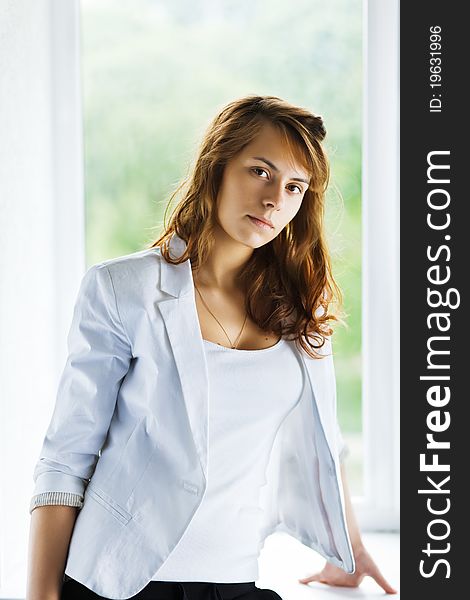 Young casual woman sitting on window