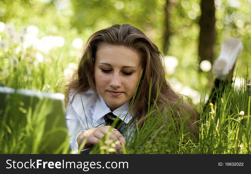 Girl with laptop lying on the lawn in thought
