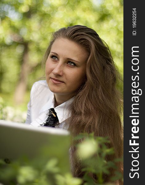 Girl with laptop lying on the lawn in thought