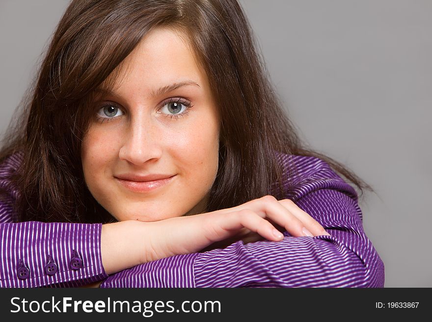 Attractive young brunette woman wearig purple shirt resting her head on crossed arms. Attractive young brunette woman wearig purple shirt resting her head on crossed arms