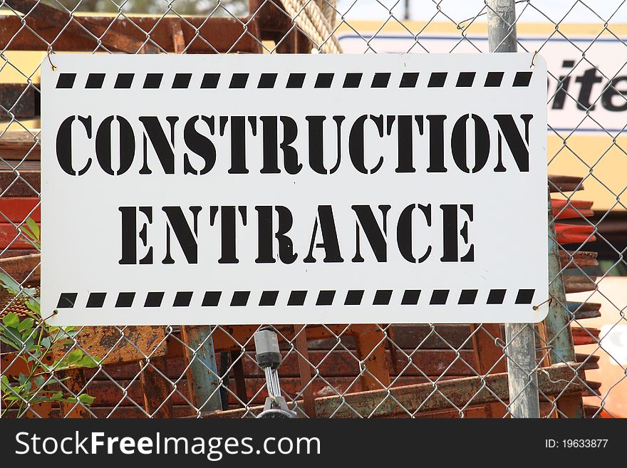 Construction Entrance sign on wire fence with materials behind it