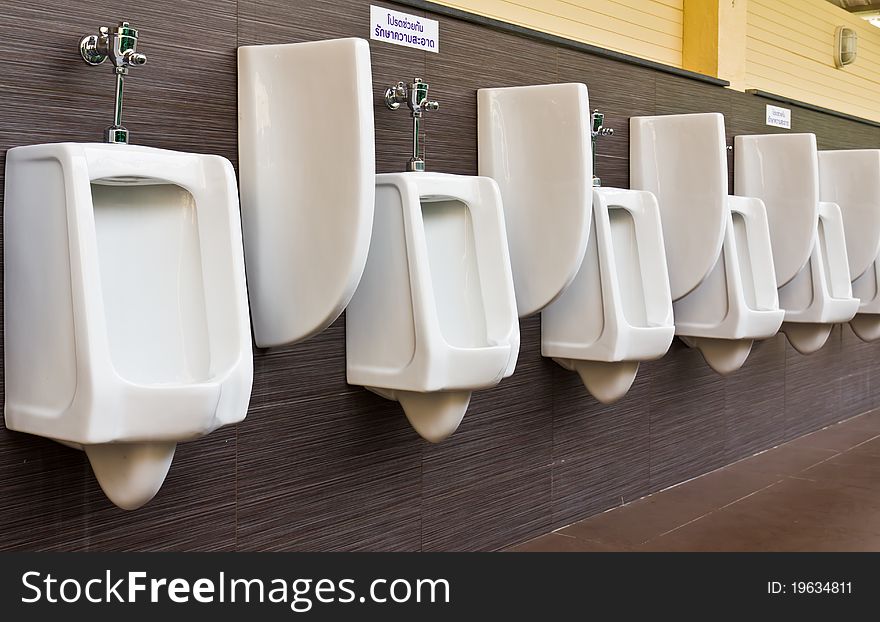 Row of white porcelain urinals in public toilets