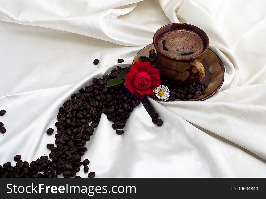 Cup of coffee with red rose on white fabric. Cup of coffee with red rose on white fabric