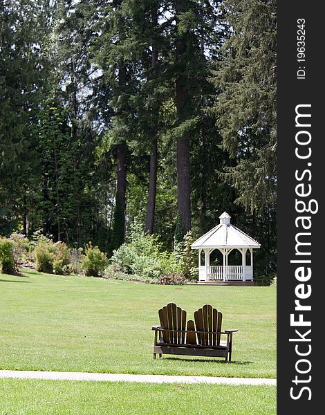 A white gazebo set on a lake backed by pine trees