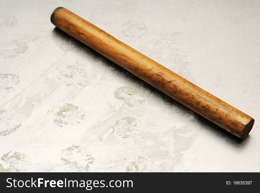 Used bakering wood roller on silver tray with dough marks at the background. The roller position at the center across the frame.