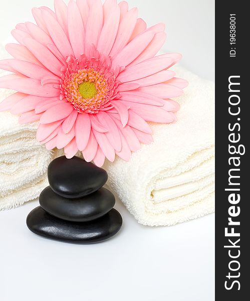 Masage stones and pink gerber, two towels isolated on a white background. Masage stones and pink gerber, two towels isolated on a white background.