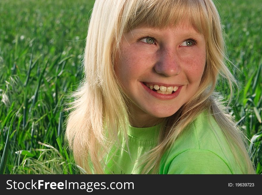 Happy young girl with smile on the  background of the green field