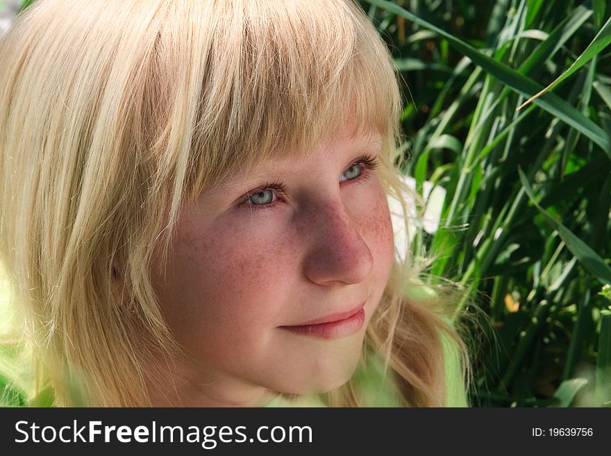 Close-up portrait of the blond young girl on the green background