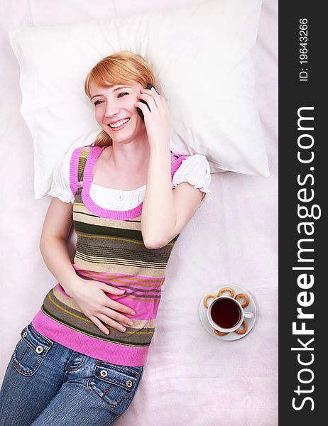 A young girl lying in bed and talking on her mobile phone. A young girl lying in bed and talking on her mobile phone