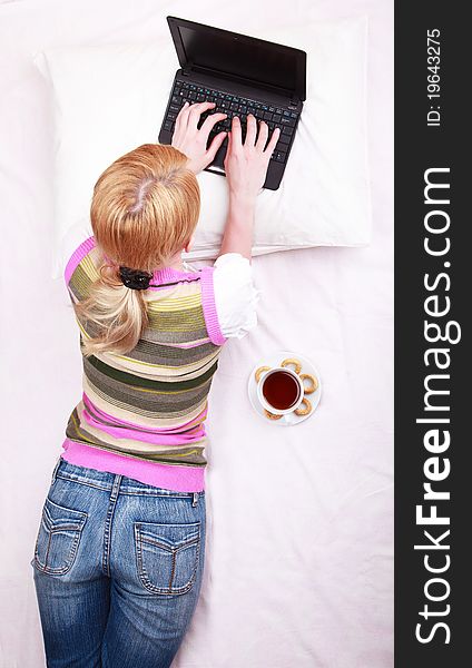 A young girl working on computer in bed. A young girl working on computer in bed
