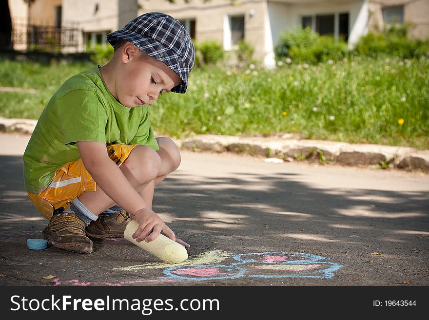 Boy drawing with chalk on asphalt
