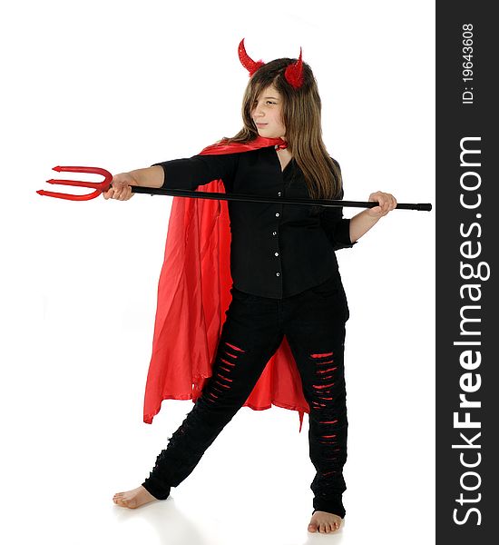 A pretty preteen dressed as a she-devil taking aim with her pitchfork. Isolated on white.