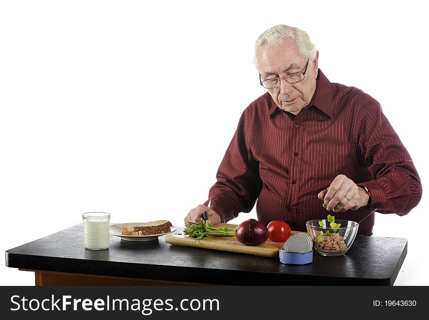 A senior man preparing a lunch composed of a tuna sandwich and a glass of milk. A senior man preparing a lunch composed of a tuna sandwich and a glass of milk.