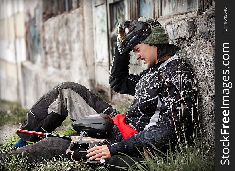 Paintball player relaxing with marker in grunge background