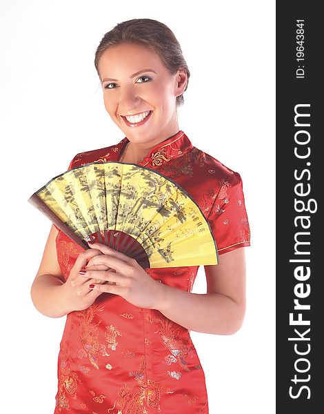 The beautiful young girl in a red Chinese dress with a yellow fan in hands. The beautiful young girl in a red Chinese dress with a yellow fan in hands