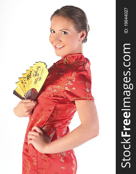 The beautiful young girl in a red Chinese dress with a yellow fan in hands. The beautiful young girl in a red Chinese dress with a yellow fan in hands