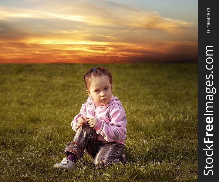 The child playing a ball on the meadow filled in with the sun