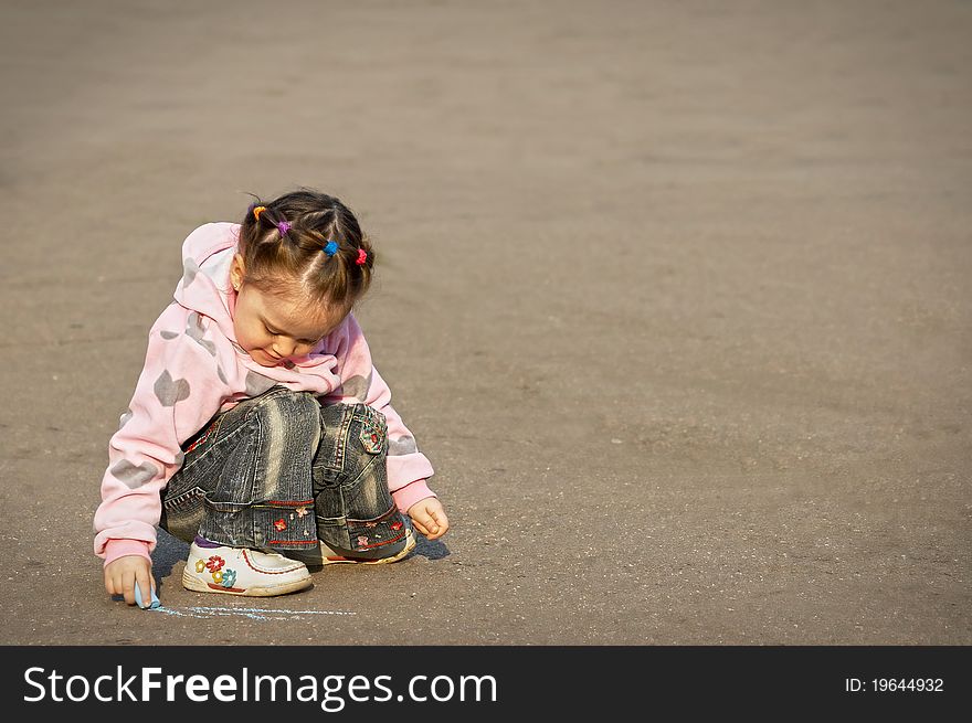 The child drawing a chalk on asphalt.outdoor