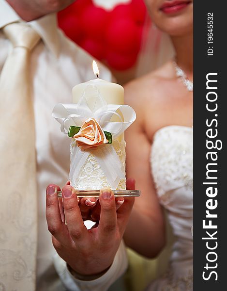 Candle in hands of newlyweds