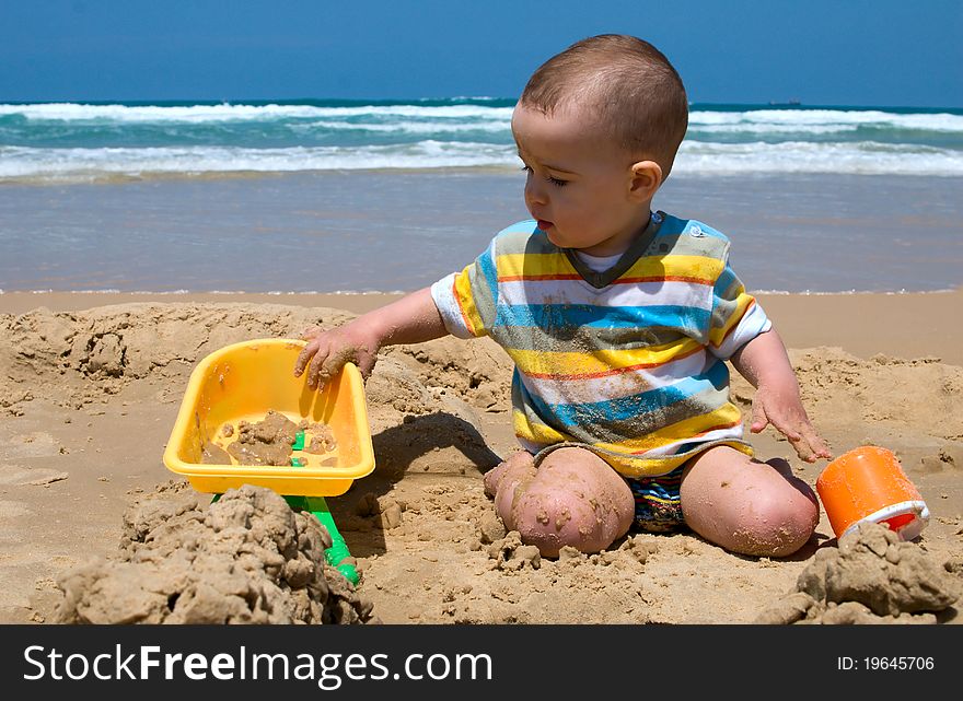 One year old child building sand castle on the beach. One year old child building sand castle on the beach
