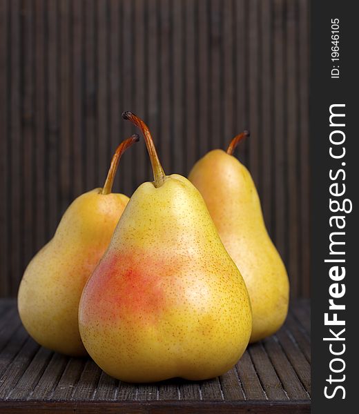 Still life of three ripe yellow pears on a wooden platform. Still life of three ripe yellow pears on a wooden platform
