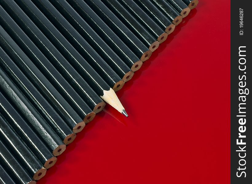 a background of one sharp black lead pencil in a row of unsharpened pencils. a background of one sharp black lead pencil in a row of unsharpened pencils