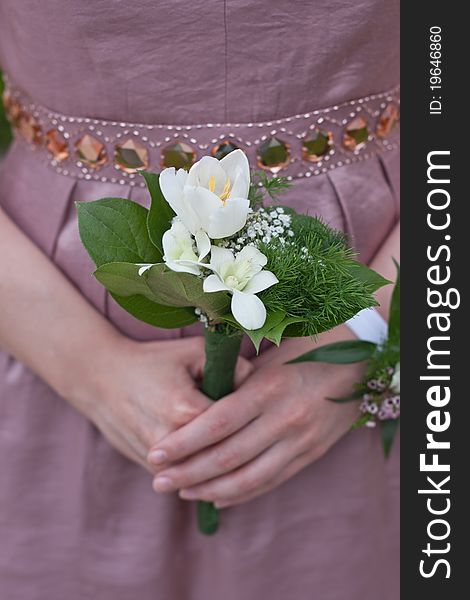 Bridesmaid holding wedding bouquet against purple dress