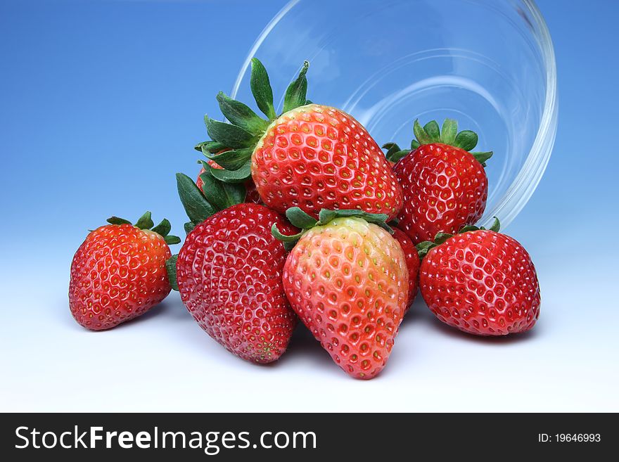 A bunch of ripe, plump strawberries spilling out of a glass bowl.