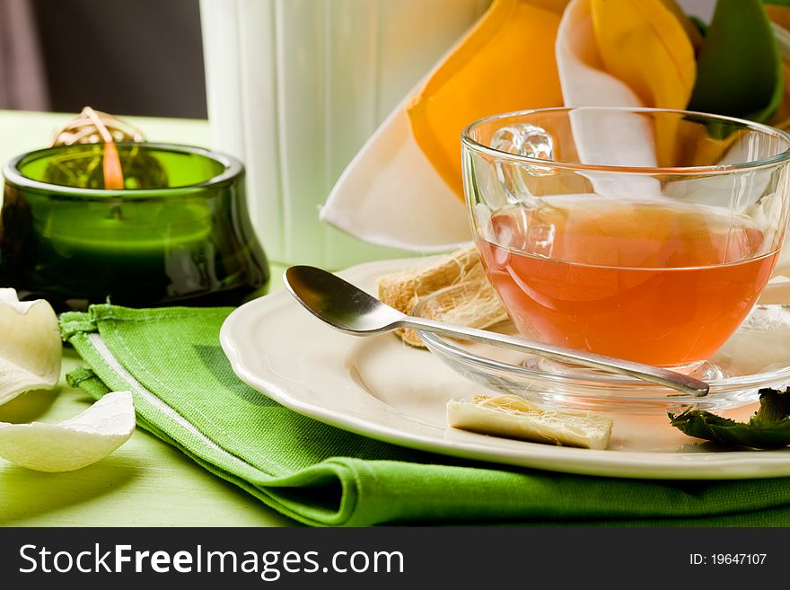 Photo of an glass cup with tea on green decorated table. Photo of an glass cup with tea on green decorated table