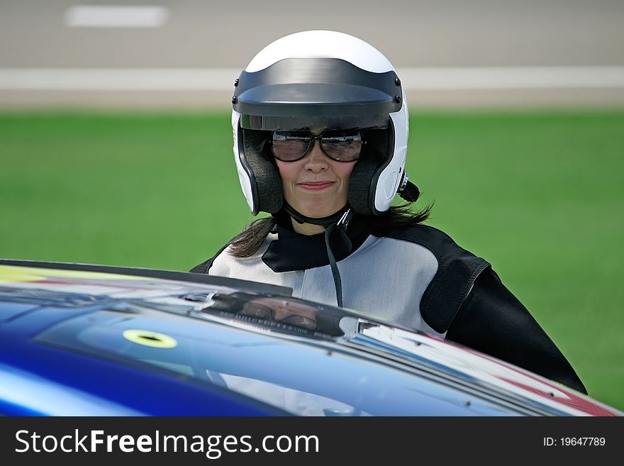 Attractive woman in motoracer uniform near race car