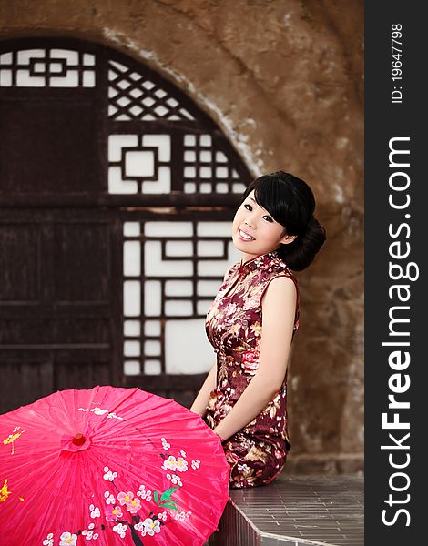 A pretty Chinese girl in cheongsam sitting outside the loess cave residence. A pretty Chinese girl in cheongsam sitting outside the loess cave residence.