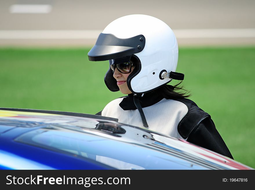 Attractive woman in motoracer uniform near race car