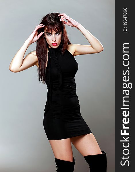 Attractive brunette model in a small black dress touching her hair and posing. Attractive brunette model in a small black dress touching her hair and posing