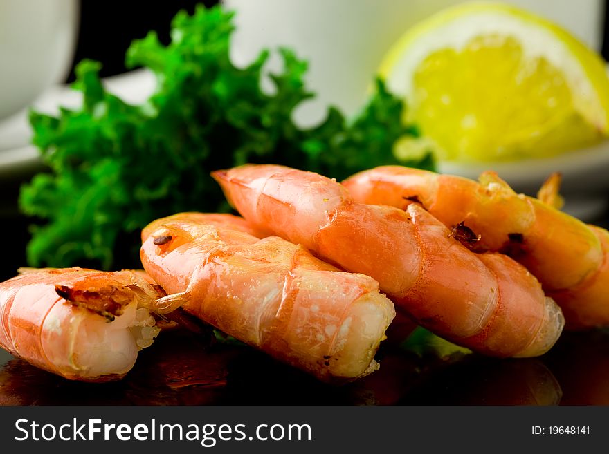 Photo of grilled king prawns on black glass table with reflection. Photo of grilled king prawns on black glass table with reflection